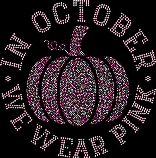 Black rhinestone shirt featuring a sparkling pink pumpkin and rainbow design with the phrase ‘In October We Wear Pink,’ supporting Breast Cancer Awareness Month.”